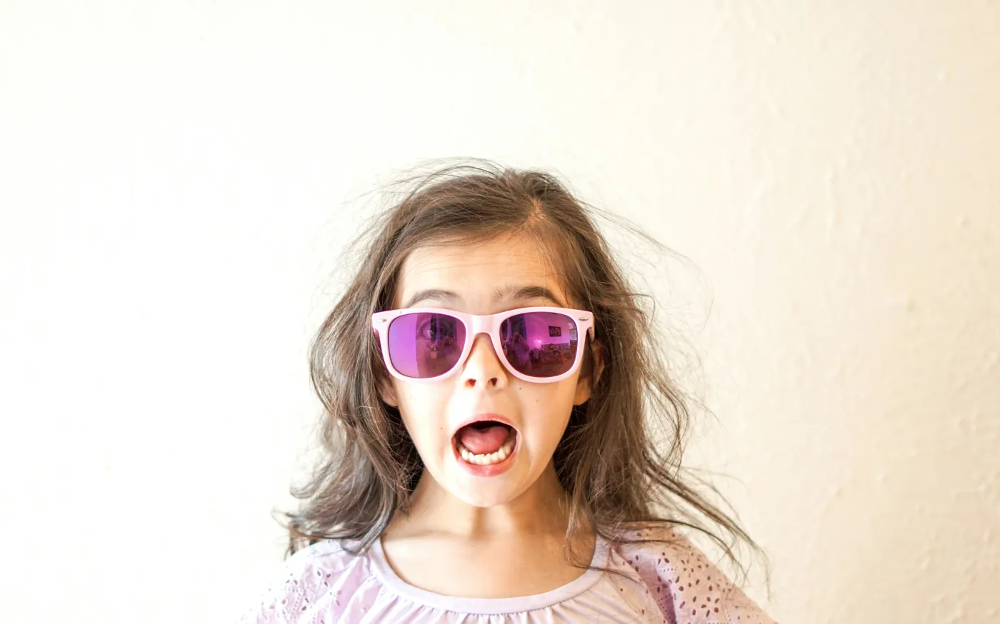 girl in white and purple floral crew neck shirt wearing blue framed sunglasses by Thomas Park courtesy of Unsplash.