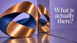 A copper and navy sculpture stands beside its mirror reflection with the words “What is actually there?”