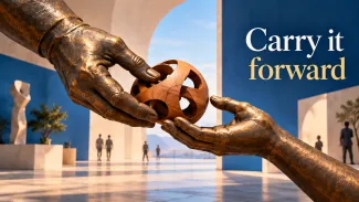 Two monumental bronze hands pass a wooden sculpture in a sunlit gallery beneath the words “Carry it forward.”