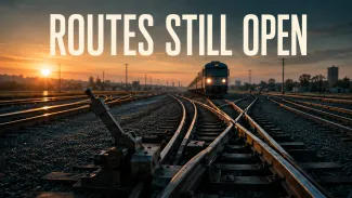 A rail switch at dawn keeps several tracks open as an approaching train nears the junction.