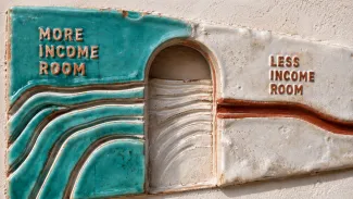 A ceramic relief shows several income channels narrowing from more income room to less income room.