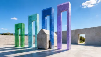 A stone house stands among four colorful architectural thresholds of different heights, representing how state tax rules can create different estate-planning outcomes.