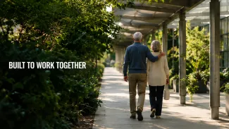An older couple walks beneath a coordinated architectural canopy beside the words “Built to Work Together.”