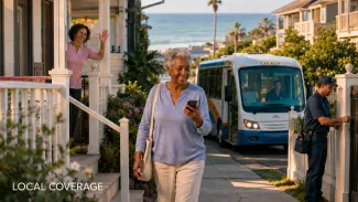 A retired woman walks through her coastal neighborhood near a neighbor, community shuttle, and local service professional.