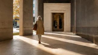 A woman walks through a sunlit stone passage toward an entrance marked “First Single Tax Year.”
