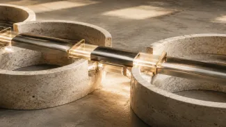 An illuminated metal flow crosses between separate stone structures through a series of engineered handoffs.