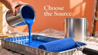 Blue paint pours from an open can into a roller tray while a larger can remains closed, beneath the words “Choose the Source.”