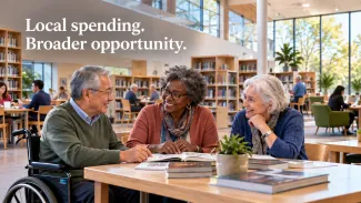Three older adults, including a wheelchair user, collaborate in a bright library beneath the words “Local spending. Broader opportunity.”