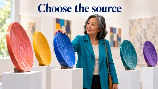 An older woman selects a blue ceramic disc among colorful gallery displays beneath the words “Choose the source.”