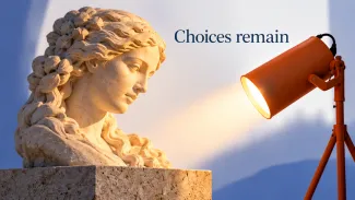 An orange adjustable spotlight illuminates a finished stone sculpture beneath the words “Choices remain.”