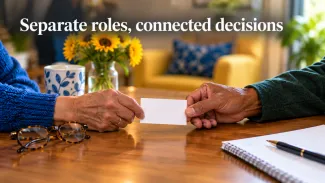 Two older adults exchange a blank contact card across a table beneath the words “Separate roles, connected decisions.”