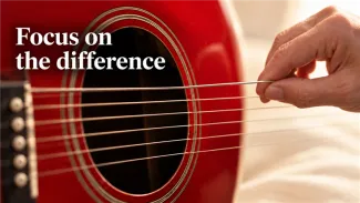 A hand plucks one string of a red acoustic guitar beneath the words “Focus on the difference”.