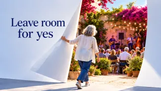 An older woman opens a giant white page onto a courtyard concert beside the words “Leave room for yes.”