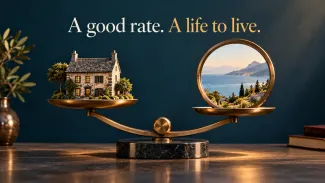 A bronze scale balances a house against a coastal view beneath the words “A good rate. A life to live.”
