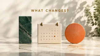 A green stone, cream calendar with one orange date, and orange disc sit beneath the words “WHAT CHANGES?”