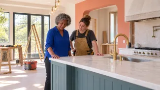 An older woman and a builder examine a new kitchen island during a sunlit home renovation.