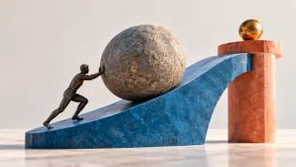A bronze figure pushes a large stone up a blue slope toward a small golden sphere.