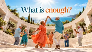 An older couple dances among friends in a seaside amphitheater beneath the words “What is enough?”