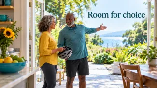 A couple talks beside open patio doors, one holding a bicycle helmet, with the words “Room for choice” above the sunny outdoor view.