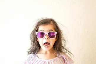 girl in white and purple floral crew neck shirt wearing blue framed sunglasses by Thomas Park courtesy of Unsplash.