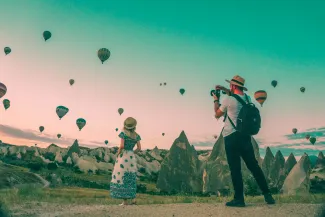 man taking photo of hot air balloons by Mesut Kaya courtesy of Unsplash.