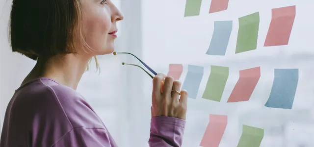 a woman looking out a window with sticky notes on it by Julia Potter courtesy of Unsplash.